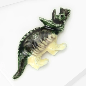 Gros plan détaillé d'une broche tricératops avec finition émaillée verte et jaune