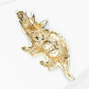 Vue détaillée du dos d'une broche dinosaure dorée avec motif en étoile texturé