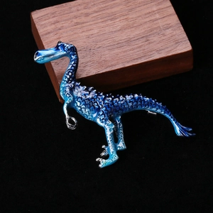 Detailed macro shot of a blue enamel dinosaur brooch featuring layered scale textures