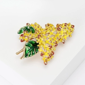 Detail of yellow hydrangea brooch with green leaves and golden enamel finish