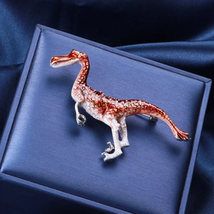 Macro shot of an orange dinosaur brooch with enamel scales on blue satin