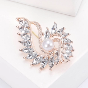 Macro view of crystal encrusted rose gold brooch with a central white pearl detail
