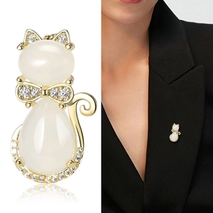 Broche chat mignonne avec opales blanches et zircons sur le revers d'un blazer noir