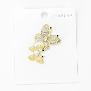 Detail of golden butterfly brooch with white zircon wings and a small pearl accent