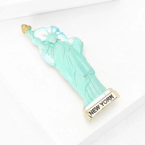 Détail d'une broche Statue de la Liberté vert menthe avec torche dorée et socle New York