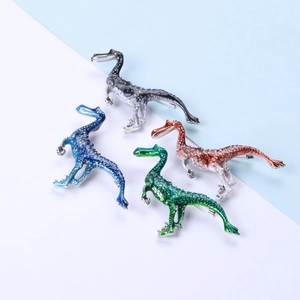 Enamel dinosaur brooches in four colors featuring detailed scale texture and artful design