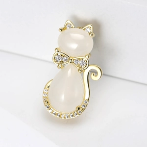 Détail d'une broche chat dorée avec pierres opales et nœud papillon en zircon brillant