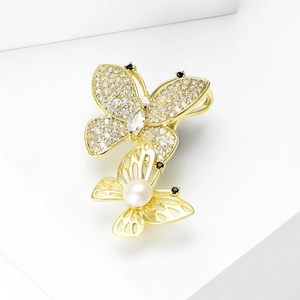 Elegant gold butterfly brooch with shimmering white zircon stones and a round pearl inlay