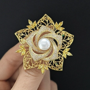 Nahaufnahme einer goldenen Kamelien-Brosche mit großer Perle und Zirkonia-Blütenblättern