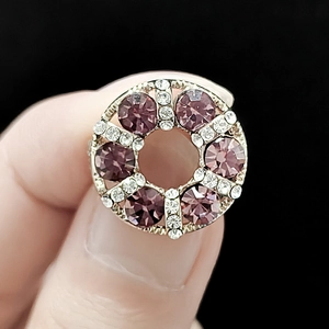 Detailed close-up of a silver-tone floral brooch with purple rhinestones and clear crystals