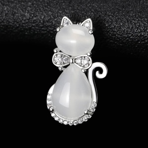 Gros plan d'une broche chat avec opales blanches et zircons sur fond noir texturé
