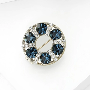 Detail of a round gold wreath brooch featuring deep blue stones and sparkling white crystals