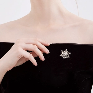 Elegant gold snowflake brooch with zircon stones worn on a black velvet dress