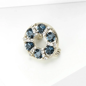 Detail of a sparkling silver circle brooch featuring navy blue gemstones and clear rhinestones