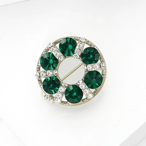 Close-up of golden wreath brooch with green crystals and sparkling white rhinestones