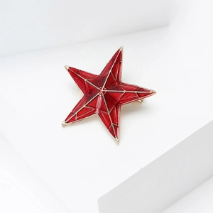 Détail d'une mini broche étoile rouge avec bords métalliques dorés et texture géométrique