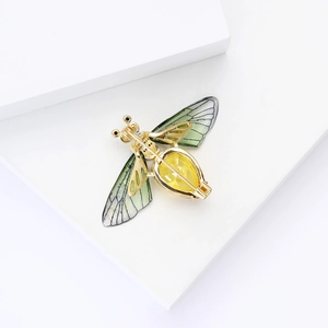 Close-up of golden bee brooch with green wings and pear-cut yellow crystal detail
