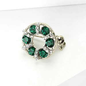 Macro detail of silver-plated wreath brooch with emerald green stones and white crystals