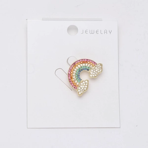 Macro detail of rainbow brooch with colorful cubic zirconia and white cloud motifs