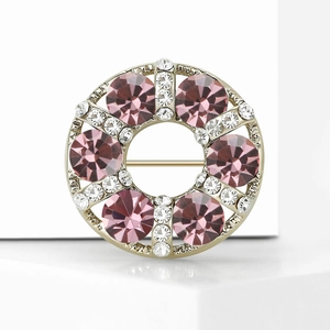 Macro detail of a light gold rhinestone brooch with pink crystals and zircon inlay