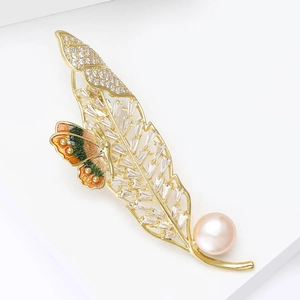 Détail macro d'une broche papillon dorée avec émail, zircons et une perle rose élégante