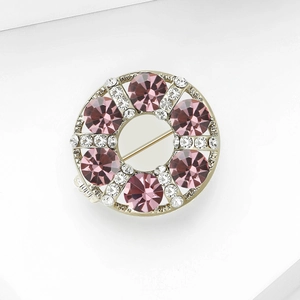Detail of flower-style circular brooch with pink crystals and rhinestones in gold finish