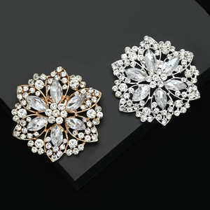 Elegant gold and silver crystal flower brooches with marquise cut stones on black pedestals