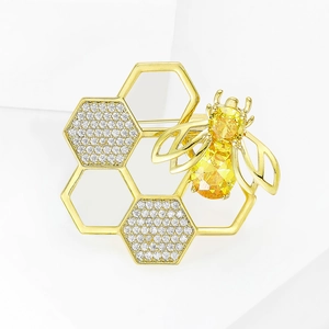 Elegant gold honeycomb brooch with rhinestones and a jeweled bee, minimalist white background