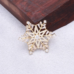 Detailed view of luxury golden snowflake brooch with cubic zirconia on textured fabric