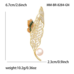 Élégante broche plume dorée avec zircone, perle et détail de papillon multicolore