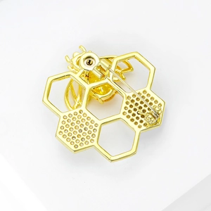 Macro detail of gold bee and honeycomb brooch featuring pave-set crystals and yellow gem