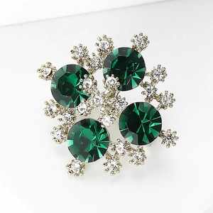 Dettaglio di una lussuosa spilla in cristallo verde con strass scintillanti in oro