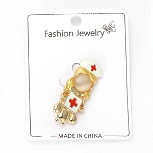 Detailed view of nurse brooch with beige opal head and red cross on white card