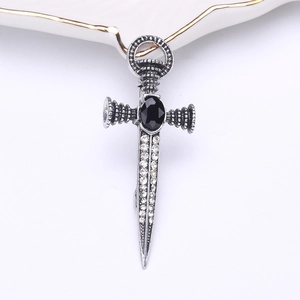 Macro detail of gothic sword brooch with black stone and rhinestones on white background
