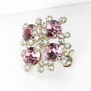 Dettaglio macro della spilla a rombo con gemme viola e strass bianchi scintillanti