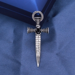 Close-up of gothic sword cross brooch with black gemstone and sparkling rhinestones