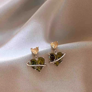 Detail of vintage heart drop earrings with olive green zircon and unique silver planet rings