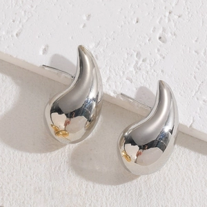 Close-up of teardrop silver earrings with small gold butterfly accents on white stone