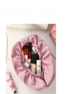 Pink satin cosmetic bag with large opening showing makeup brushes and perfume inside
