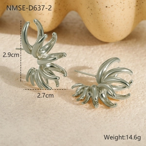 Détail macro de boucles d'oreilles géométriques en acier argenté sur fond beige