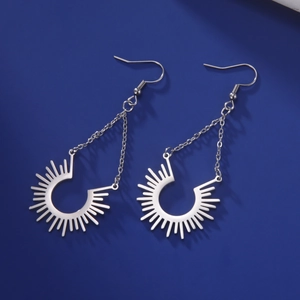 Détail macro de boucles d'oreilles pendantes soleil en acier inoxydable poli