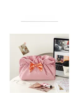 Pink cosmetic bag with a large red satin bow and cloud-shaped褶皱 folding opening