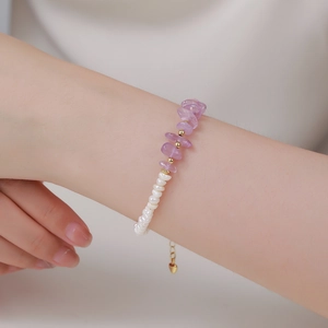 Close-up of baroque pearl and purple amethyst bracelet with a gold heart charm