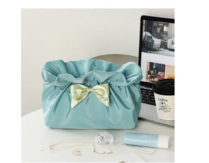 Detailed view of blue fabric cosmetic bag with ribbon bow on desktop with coffee