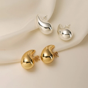 Elegant gold and silver teardrop stud earrings with polished mirror finish on silk