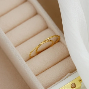 Macro detail of twisted and faceted minimalist 18K gold plated rings in a jewelry box