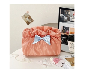 Detail of coral pink cloud cosmetic bag with satin pleats and blue ribbon bow