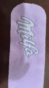 Detailed close-up of light purple knit fabric with miya embroidery on a wooden surface