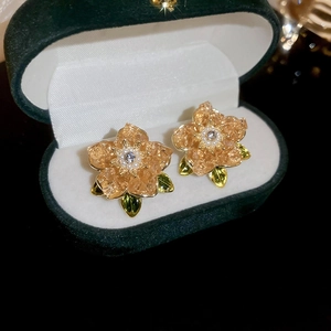Detail of emerald floral stud earrings with amber petals and pearls in a green velvet box