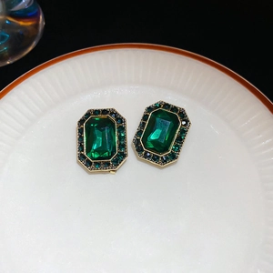 Close-up of vintage emerald green oval stud earrings with dark green crystal halo